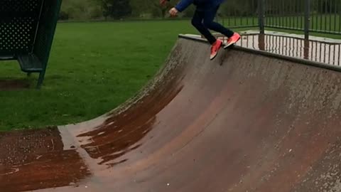 Blue jacket orange shoes girl slips on skateboard half pipe