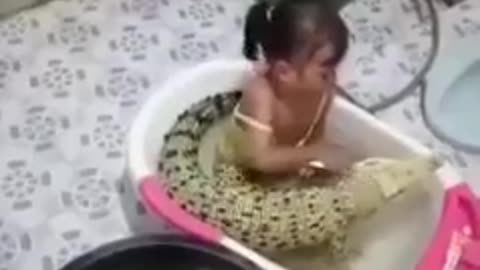 Child bathes with an alligator and a snake beside him