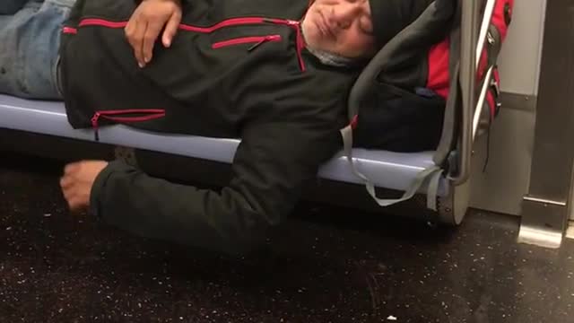 Man black jacket beanie asleep on train