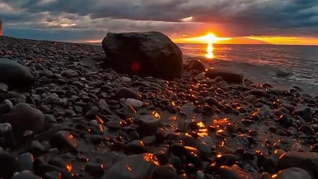 Beautiful beach, rising sunlight scattering like gold on rock.