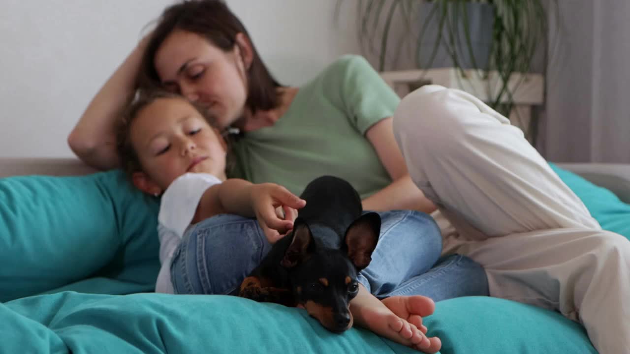 Mother and daughter having a good time with their dog at sofa