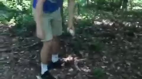 Guy in blue shirt smashes long lightbulb against tree