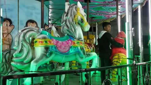 Cute baby playing by riding on toy horse.