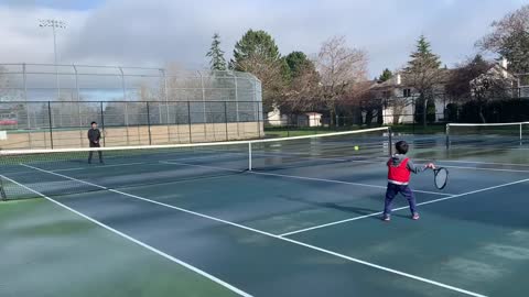 6 years old boy plays tennis with his 14 years old brother