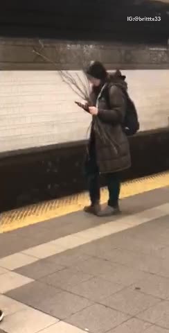 Girl in big jacket in subway holding a bunch of branches