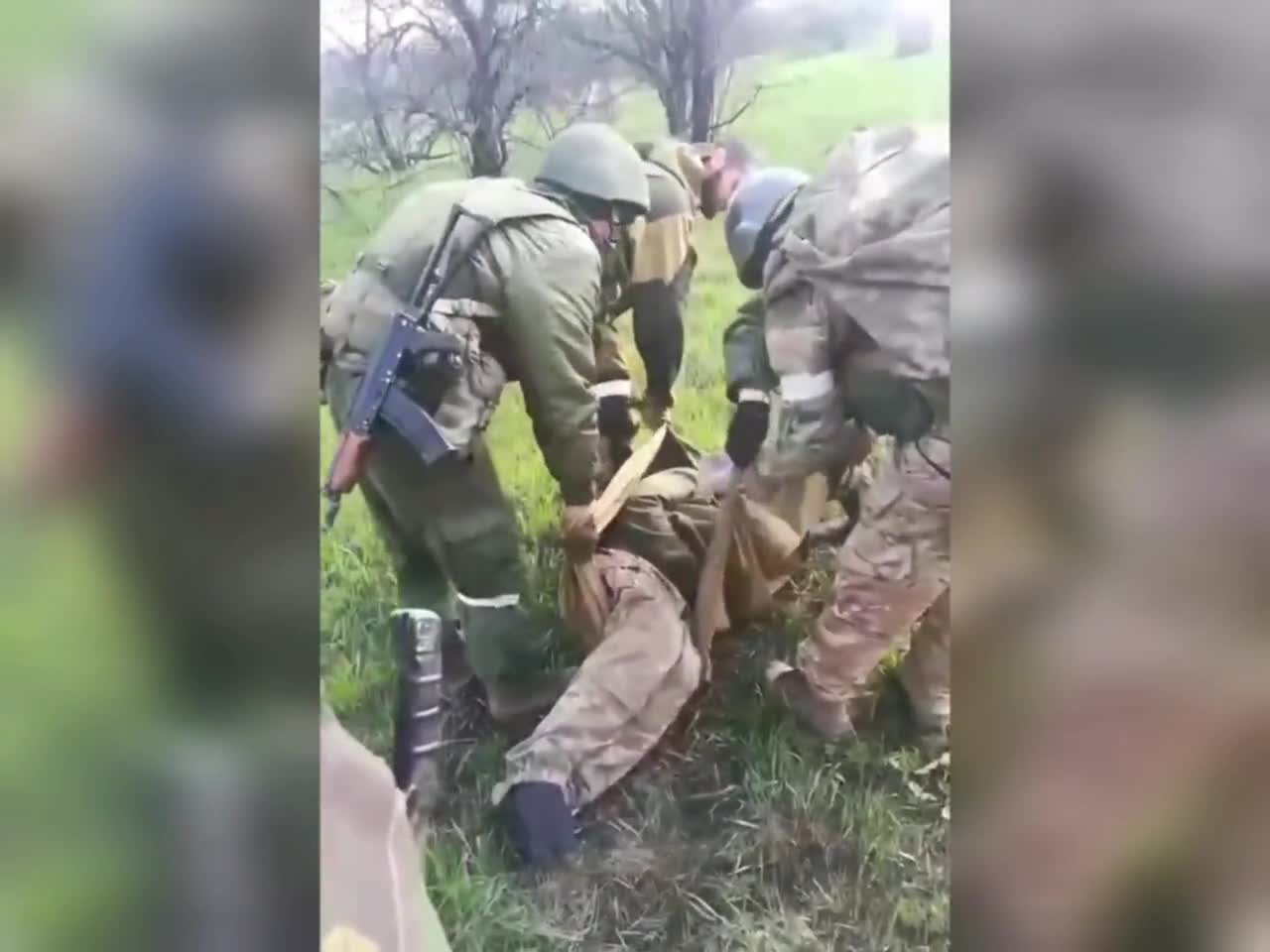 Russian soldiers carry a wounded Ukrainian serviceman