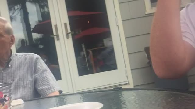 Man in white shirt shotguns beer in front of grandpa