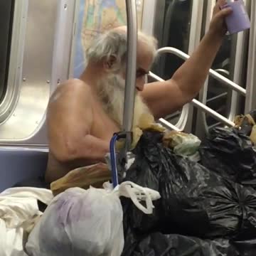 Shirtless homeless man applying on lotion in subway train