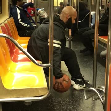 Man dribbles ball on subway train