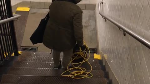 Woman pushes vacuum down public stairs