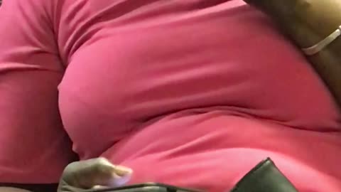 Woman in pink flossing her teeth on train