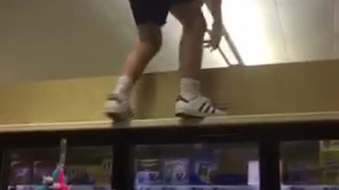 Man walks on top grocery fridge