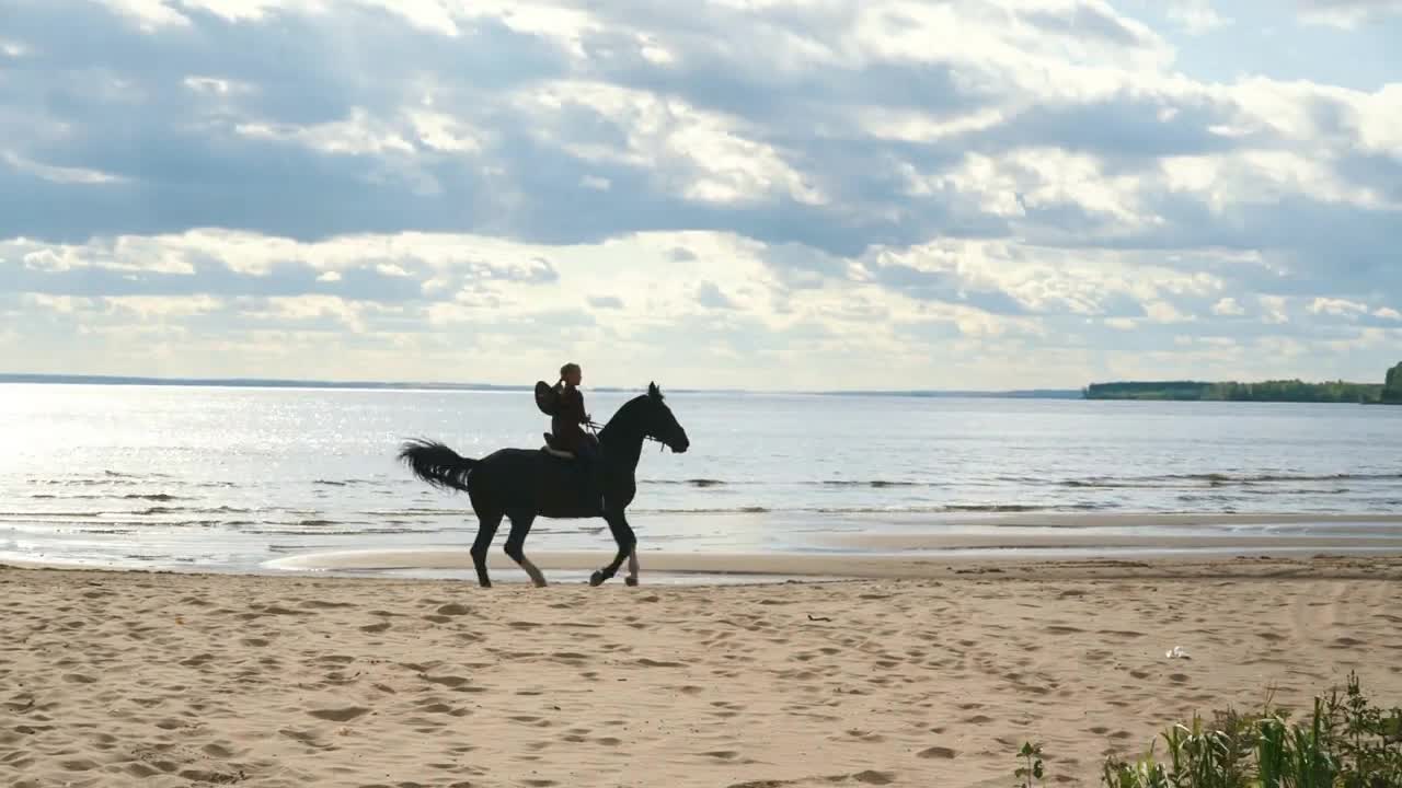 Girl riding a horse on coastline at the beach in early morning