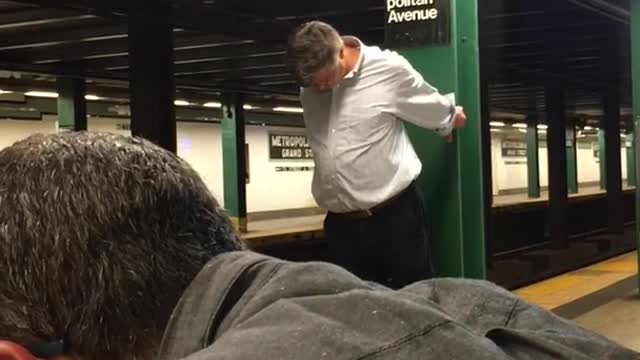 Man in blue holding on to green pole