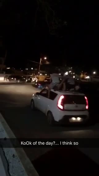 Night time three guys on top of kia soul car paddling while car is moving driving
