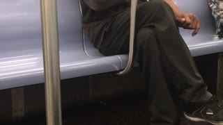 Older man in all black laughing on subway