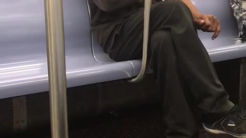 Older man in all black laughing on subway