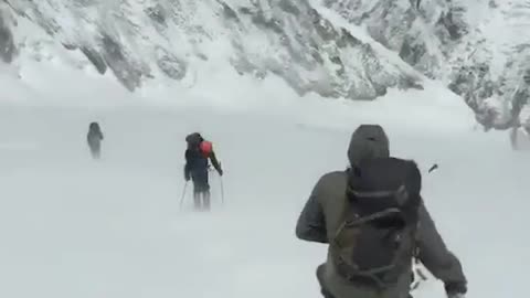 A man waling in snow with wind blowing