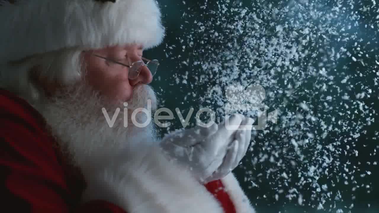 Santa Claus blowing snow from hands in slow motion