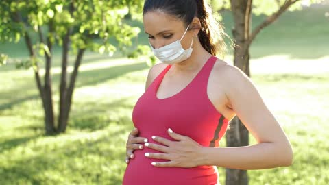 Pregnant woman with mask in the park