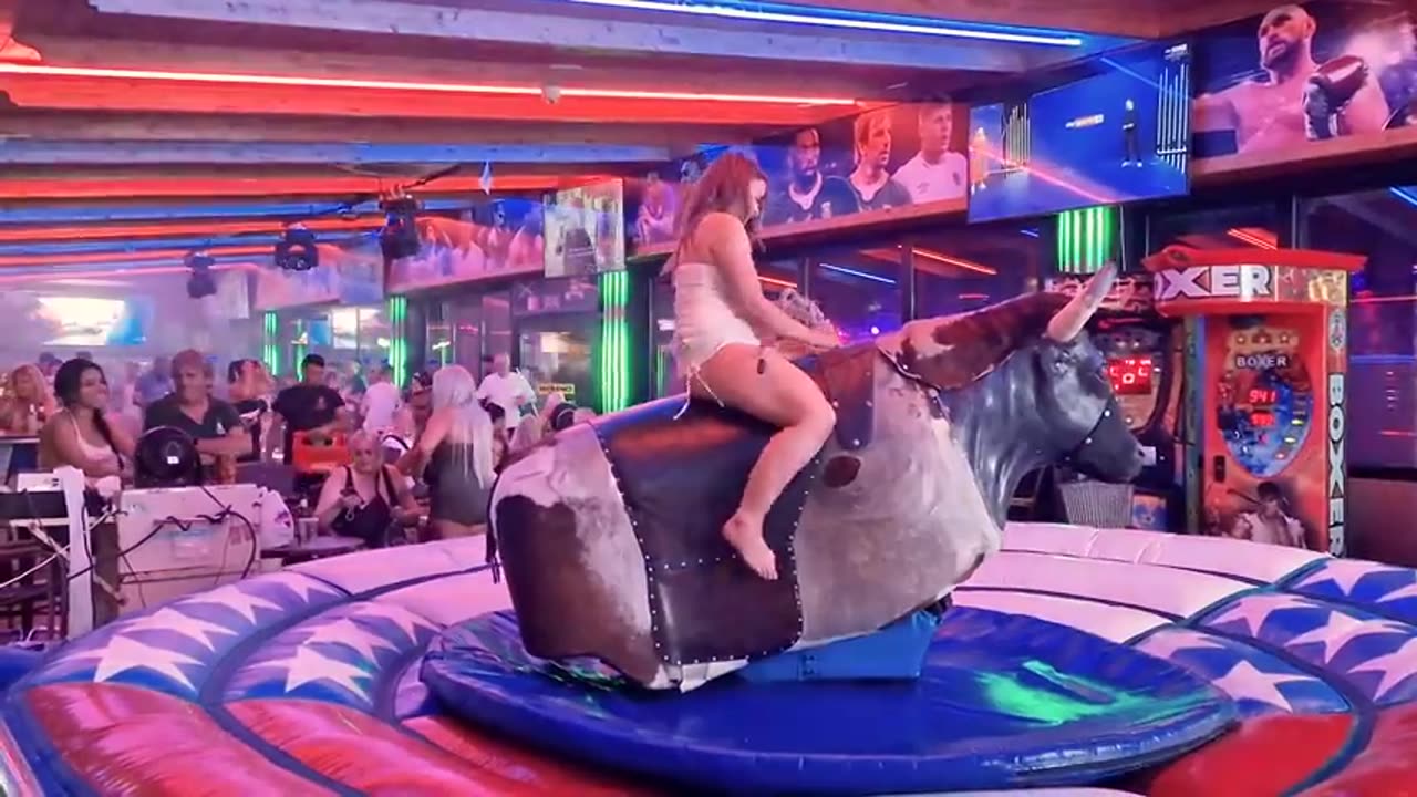 Pretty Girl in Beautiful Dress Riding on a Bull in Benidorm