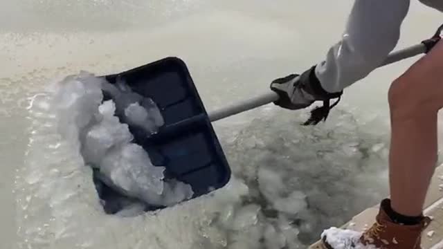 2 crazy men break ice in a frozen pond and take an ice bath in it