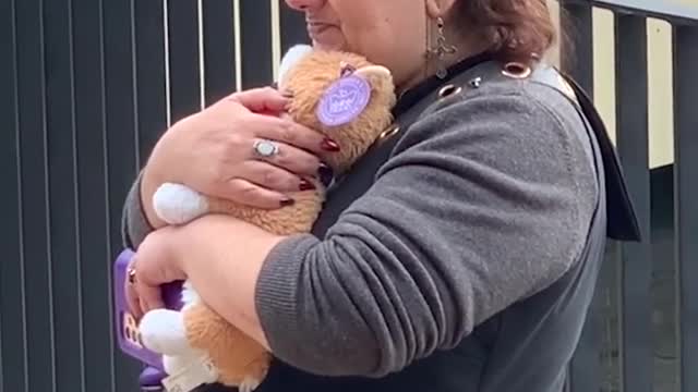 Lady cuddles toy corgi whilst watching Queen's funeral