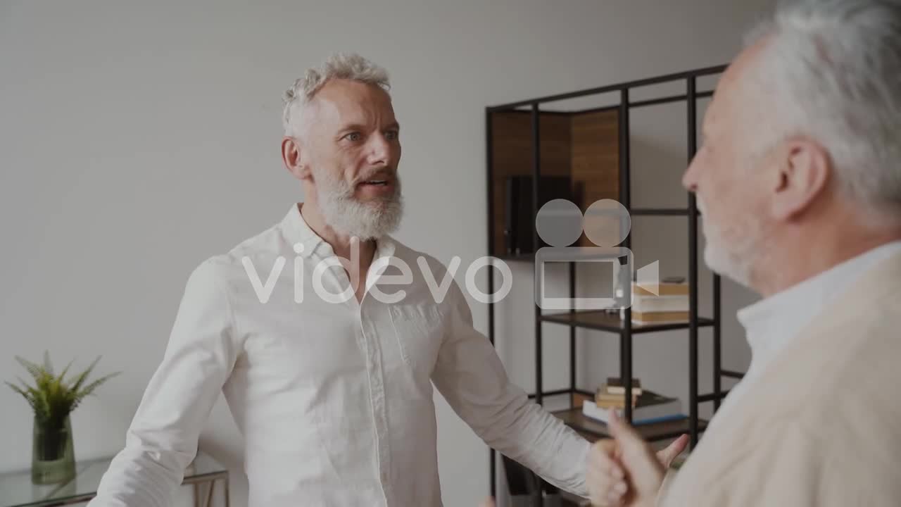 Two Happy Senior Men Friends Talking And Laughing At Home