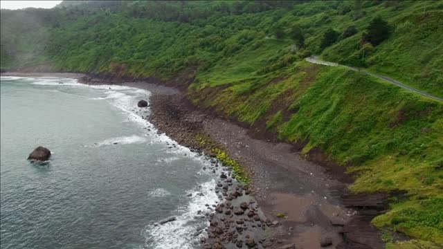 aerial shot above dramatic path between rocks mountain foggy forests and ocean at rainy cloudy day