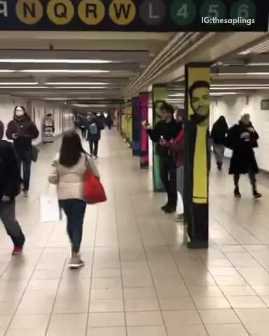 Subway musician plays guitar and sings, two guys bow their heads up and down the to beat