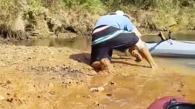 Red kayak blue shirt stuck in mud