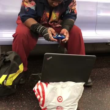 Guy playing games on subway laptop controller target bag