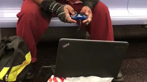 Guy playing games on subway laptop controller target bag