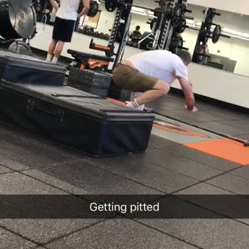 Balding guy in gym practicing how to stand up on surfboard