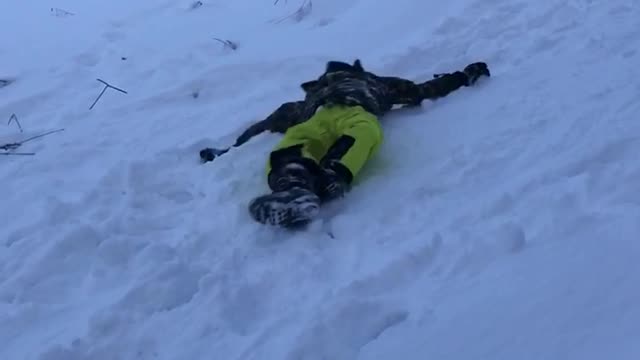 Guy green pants rolling down snow hill