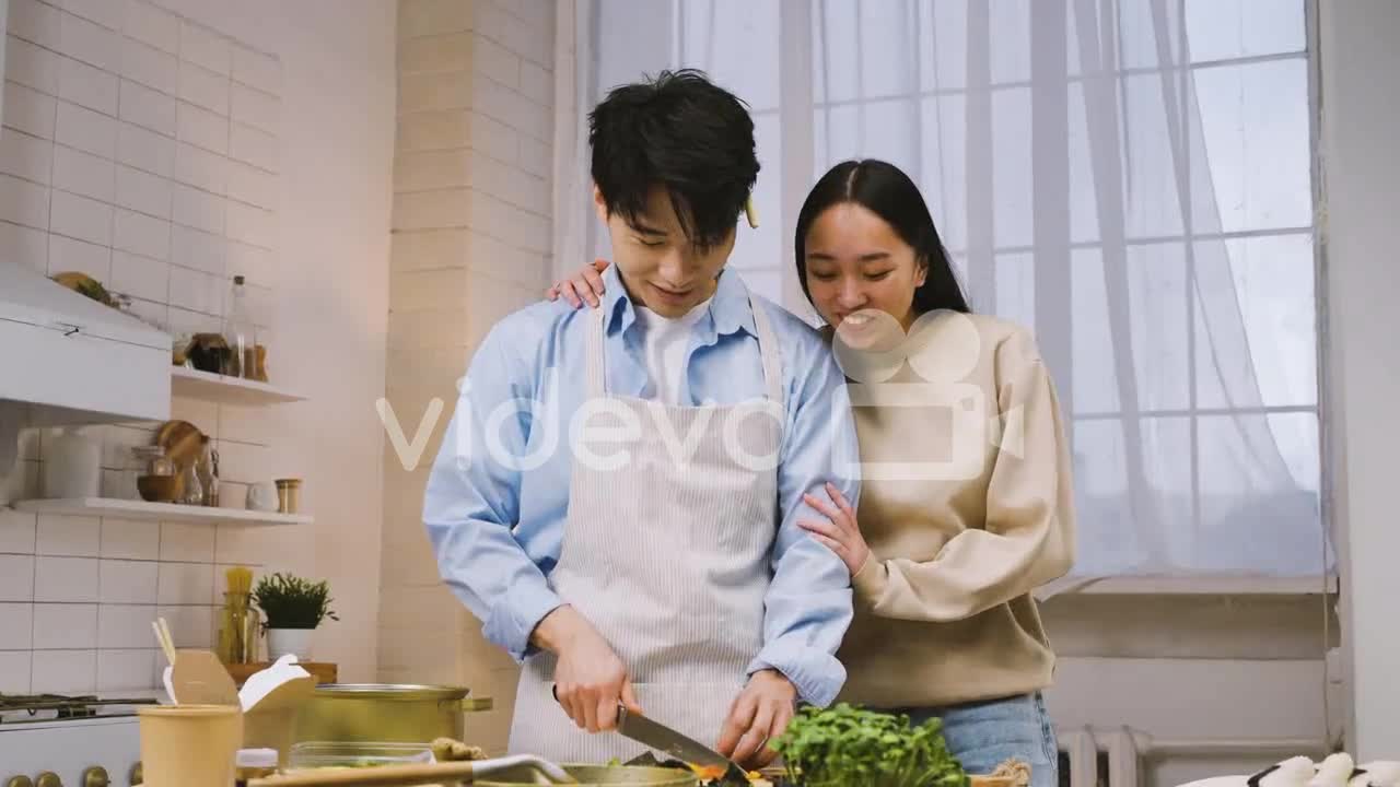 Japanese Man Cutting Ingredients In The Kitchen, Then Her Female Friend Approachs And Talk With Him