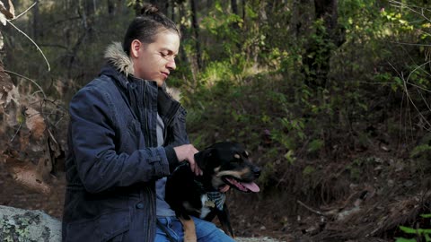 Man pets his dog in the forest