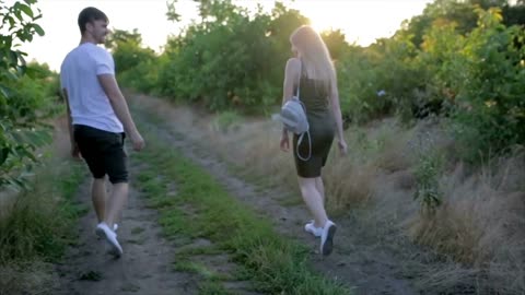 Young happy couple in love with dog having fun outdoors in lupines at sunset