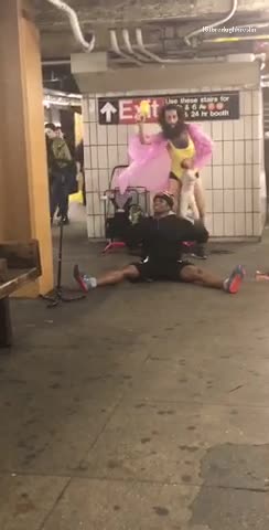 Guy pink shirt yellow body suit on unicorn singing running subway