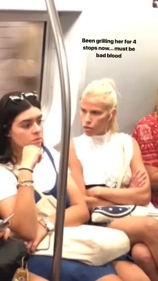 Angry blonde girl staring down girl next to her subway sitting