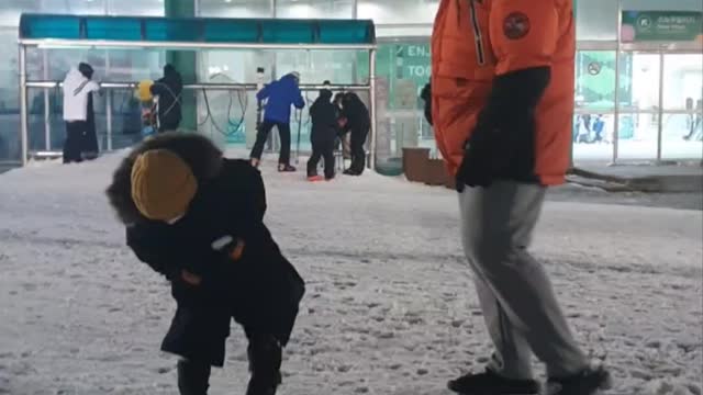 Baby playing soccer with a ball made of snow