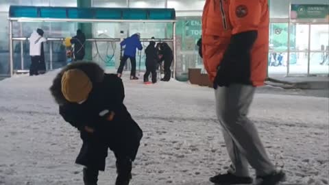 Baby playing soccer with a ball made of snow