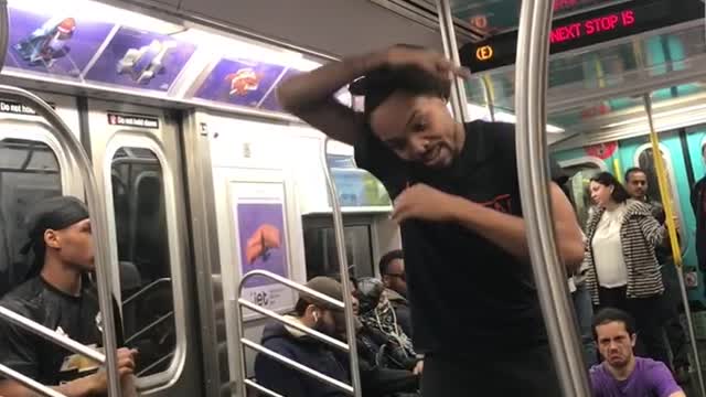 Man in purple shirt dancing around crowded subway