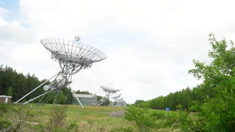 Large satellite dishes lined up on a plain in nature