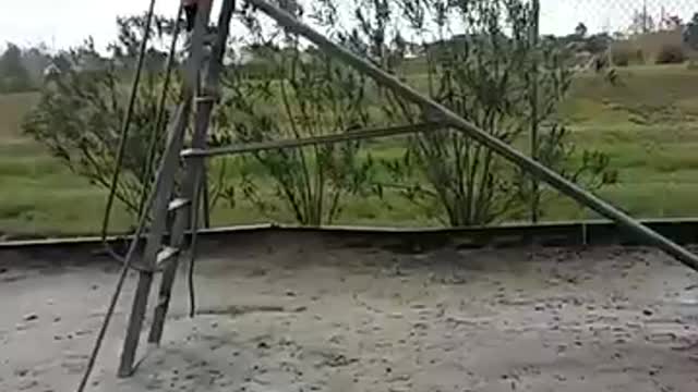 Guy in grey sweatshirt tries to stand up on a slide and ends up falling down