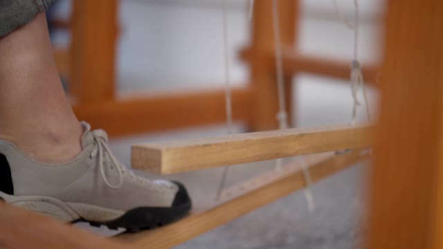 Close up of a Person's Foot Stepping on the Treadles of a Loom