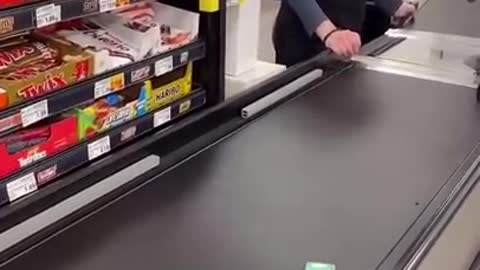 Cashier is waiting on tictacs to go all the way down the conveyor belt.