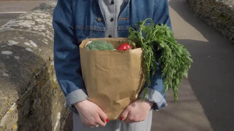 Tracking Shot of Young Woman Walking with Bag of Groceries