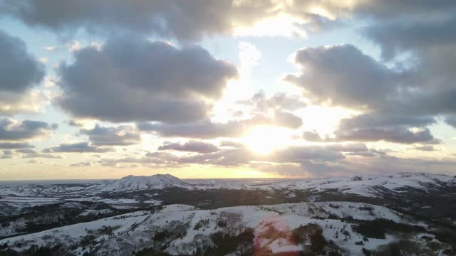 Gorgeous Time Lapse Drone Shot of a Snowy Hilltop in a Cloudy Sky