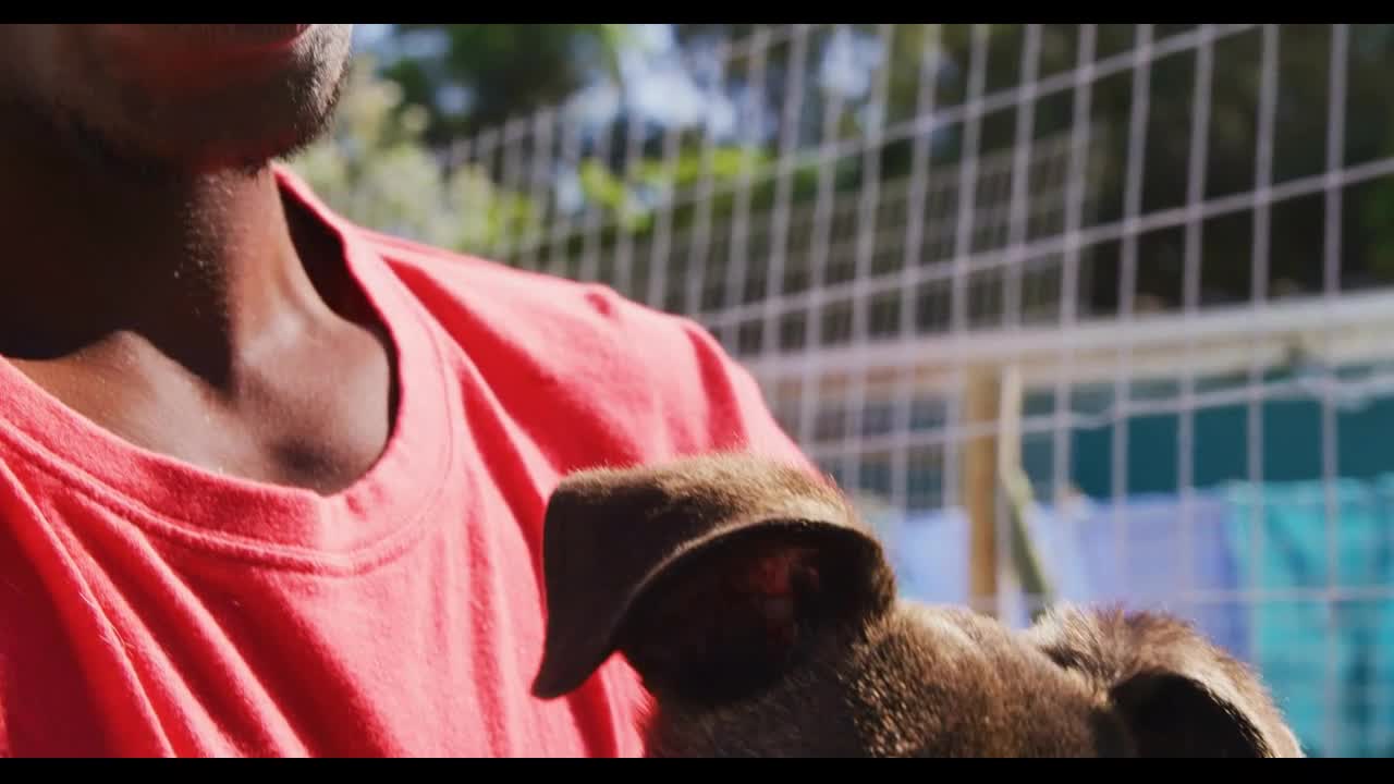 African American volunteer man in a dog shelter with a puppy